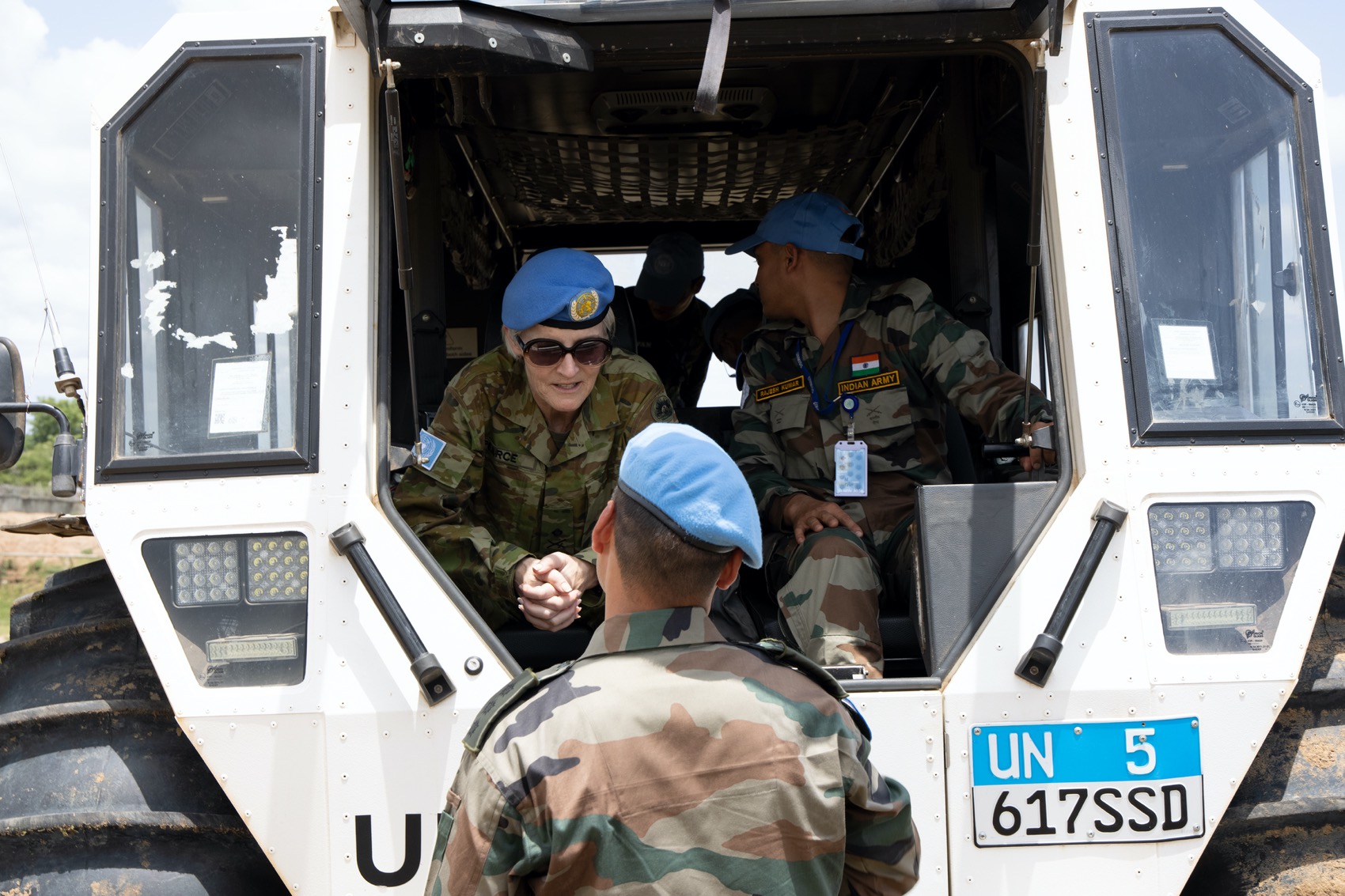 UN peacekeeper speaking to a superior officer seated in a vehicle.