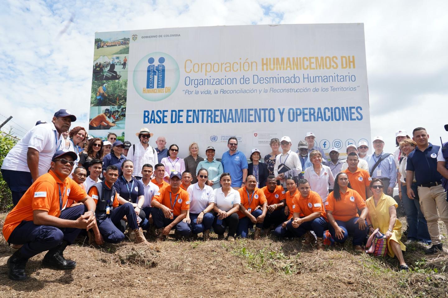 Large group of people posed in front of a large sign.