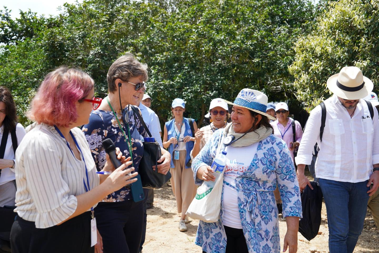 Group of people outdoors with women in the center in conversation.