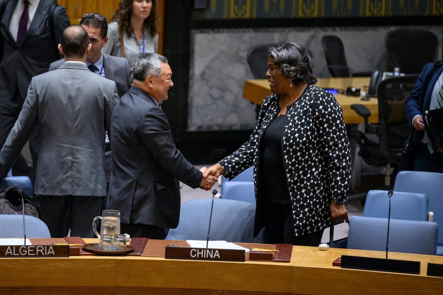 Man and woman standing behind table shaking hands.